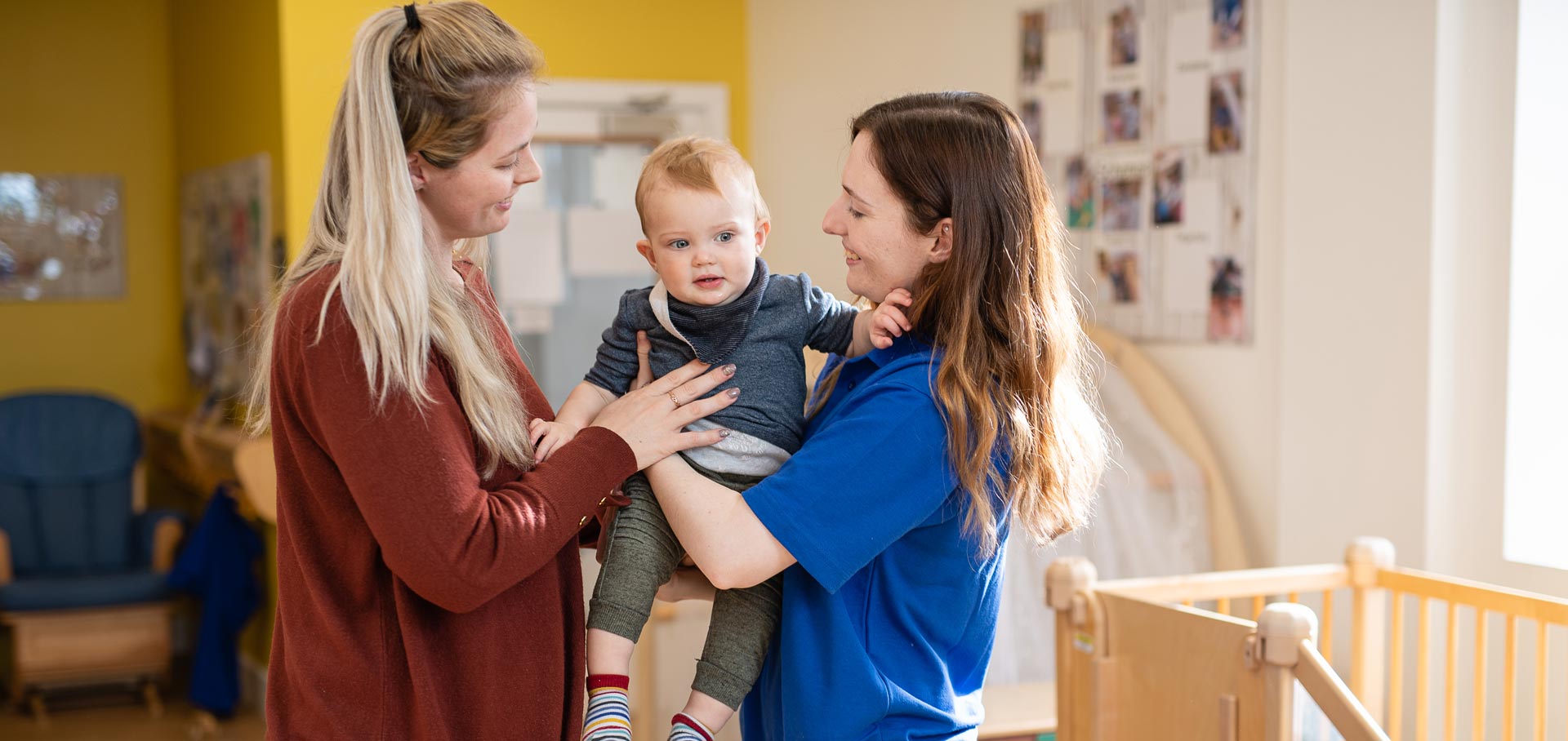 A mother giving her baby to a nursery worker