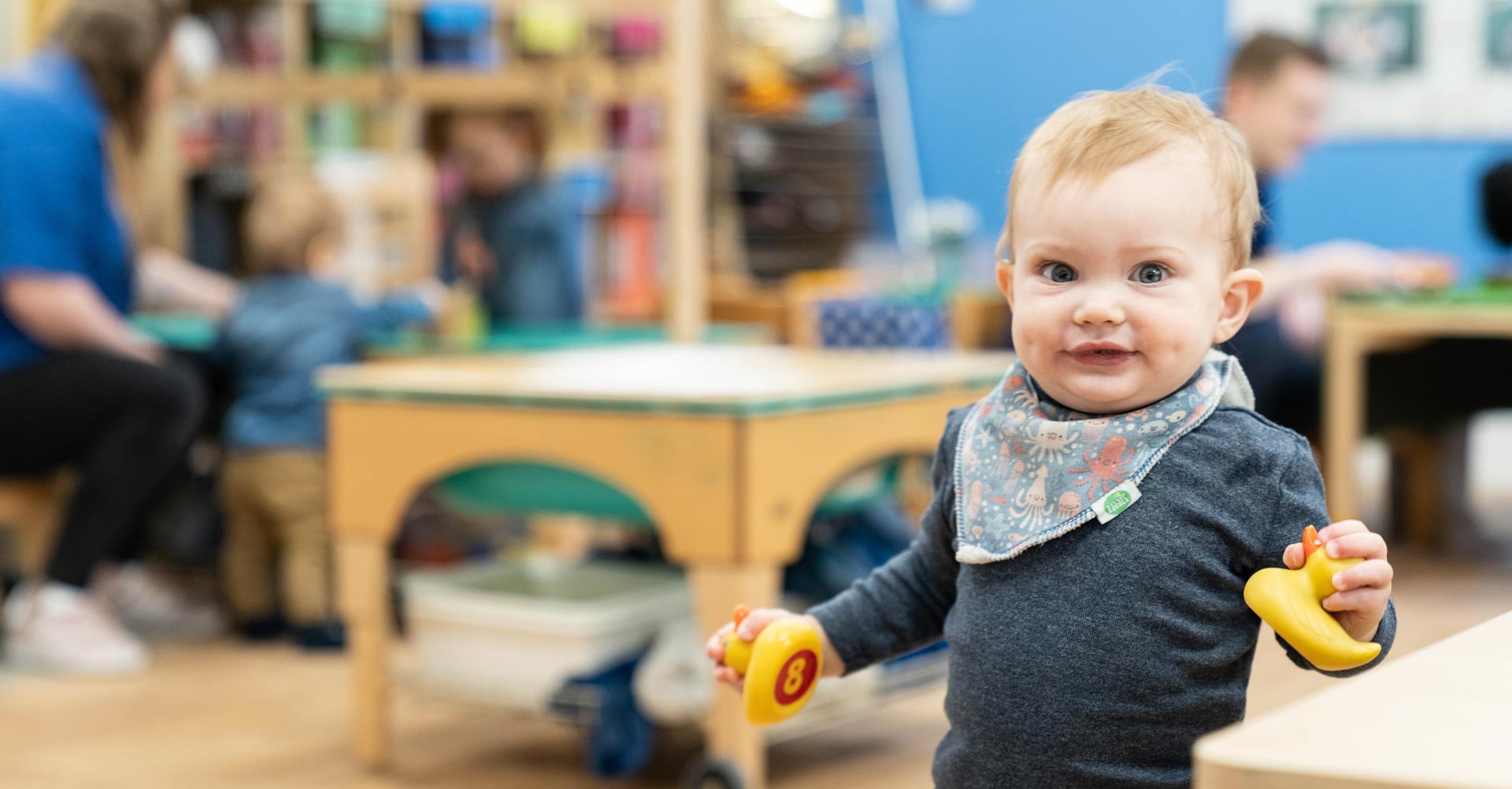 A toddler holding 2 rubber ducks