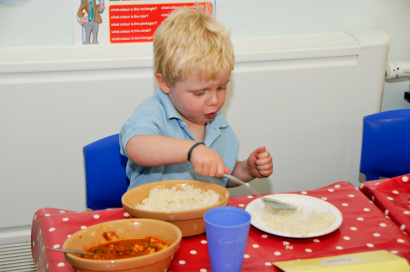 A young child dishing his lunch out