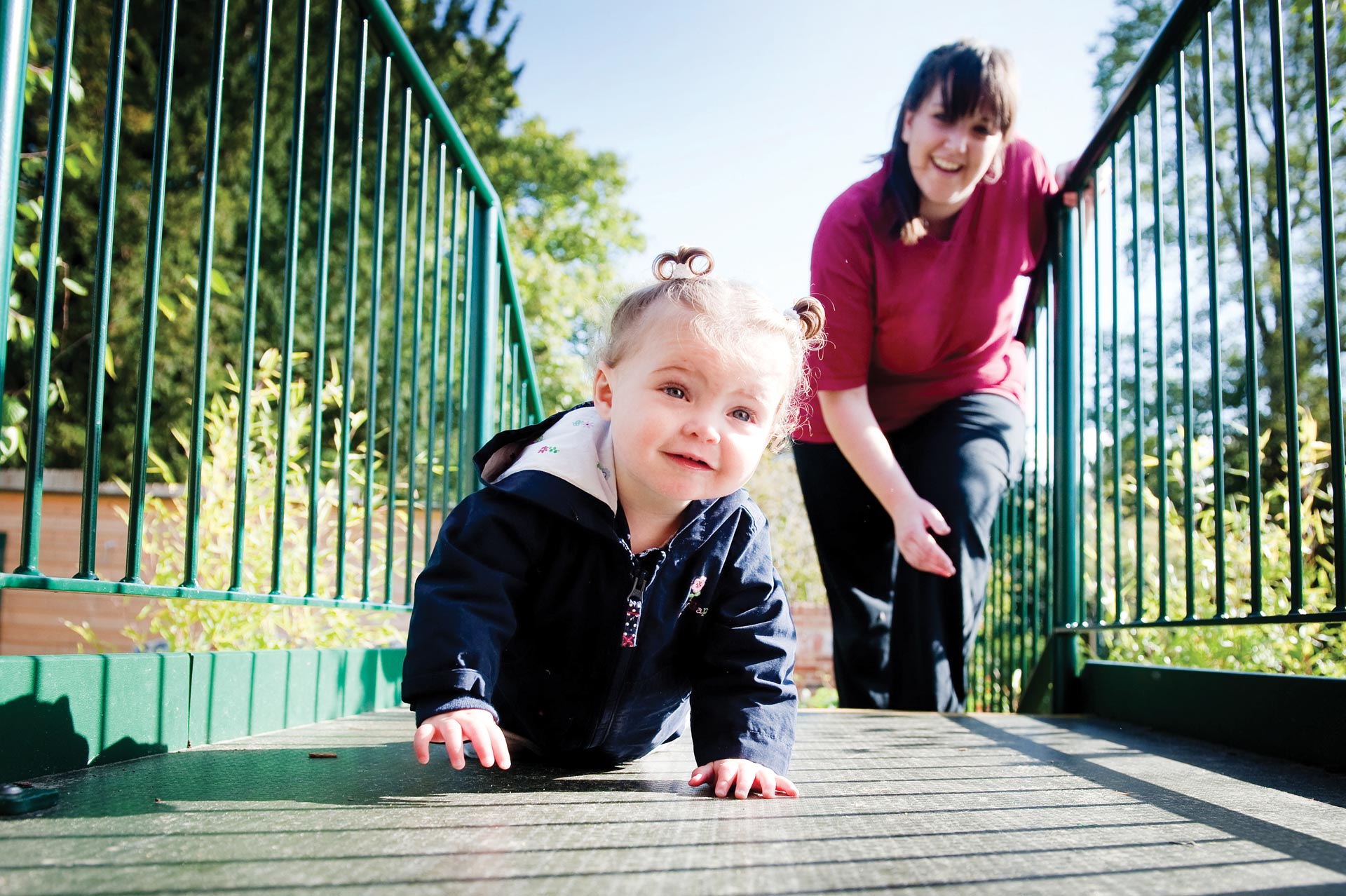 A child crawls whilst an adult supervises