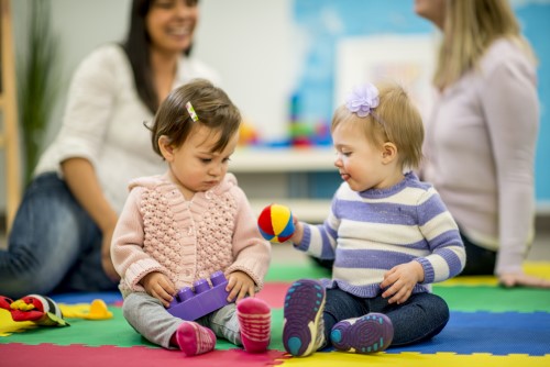 Smiling mum holding her baby while talking to a the nursery manager